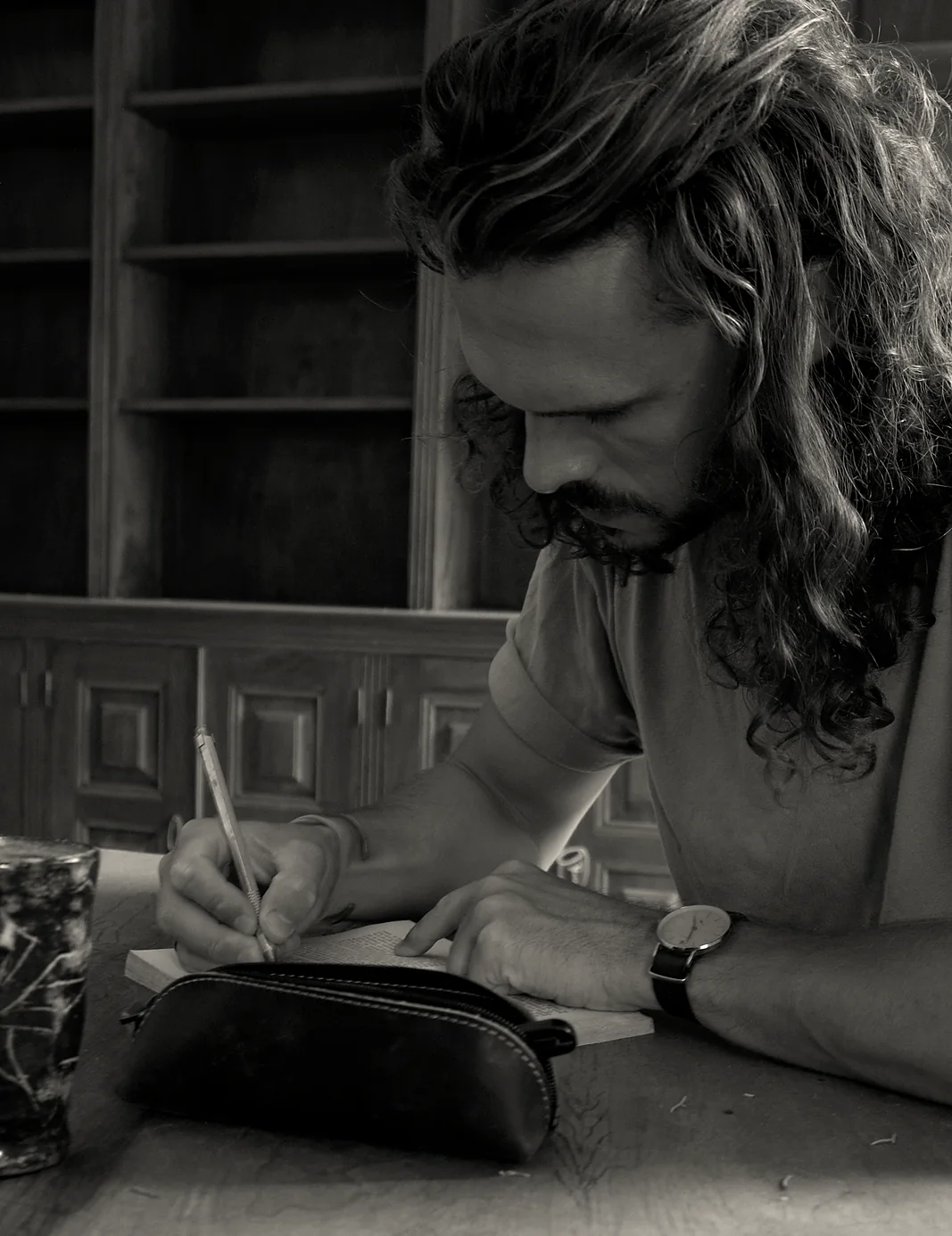 Charly, fondateur de Bifröst, écrivant dans un carnet à une table de bois